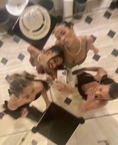 three women are taking a selfie in the mirror while another woman takes a photo