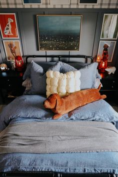 a bed with blue sheets, pillows and pictures on the wall above it in a bedroom