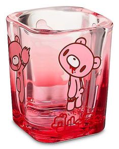 a red glass with a cartoon bear on the front and bottom, sitting next to a candle holder