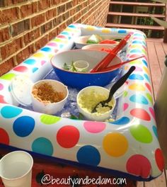 an inflatable picnic table with bowls and utensils on it, next to a brick wall