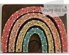 a string art kit with an arch and rainbow in the middle on a wooden board