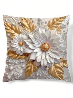 a decorative pillow with white flowers and gold leaves on the front, sitting on a white surface