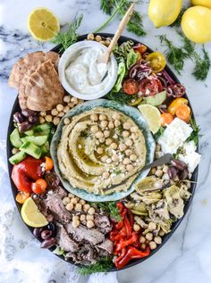 a platter filled with hummus, olives, tomatoes, lettuce and other vegetables