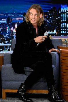 a man sitting on top of a blue couch in front of a table with a microphone