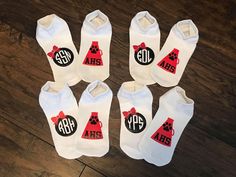 six pairs of white socks with red and black dog paw prints on them, sitting on top of a wooden floor