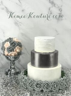 three tiered wedding cake with roses on the top and silver trimmings sitting next to each other