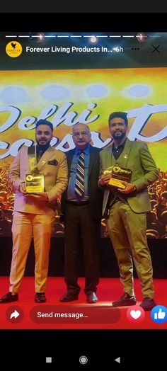 three men standing next to each other on a red carpet holding gold items in their hands