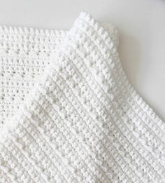 a white crocheted blanket laying on top of a table