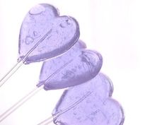 three purple heart shaped kites flying in the sky