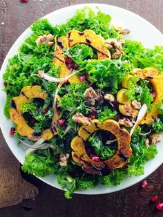 a white plate topped with lettuce, squash and pomegranates