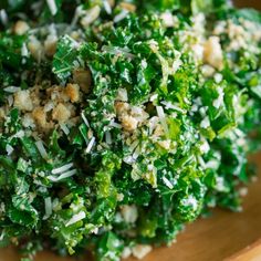 a wooden bowl filled with lots of green vegetables and toppings on top of it