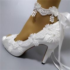 a woman's white wedding shoes with lace and bows on the heels are shown