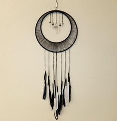 a black and white dream catcher hanging on the wall with feathers dangling from it's sides