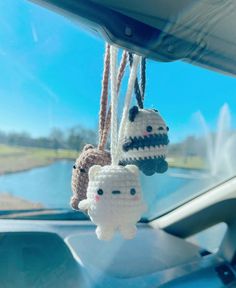 three crocheted animals hanging from the dashboard of a car