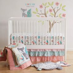 a baby crib with an elephant and tree decal on the wall next to it