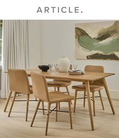 a dining room table with four chairs and a painting on the wall behind it in front of a window