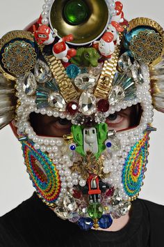 a man wearing a mask made out of beads and other items on his face,