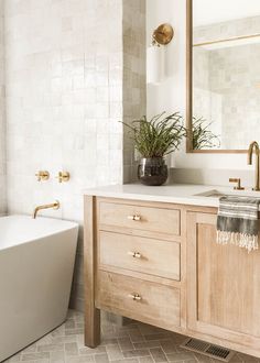 a bathroom with a tub, sink and mirror