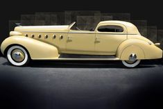 an antique yellow car is parked in front of a black background