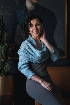 a woman posing for a photo in front of a painting