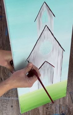 a person is painting a church on a piece of wood with acrylic paint
