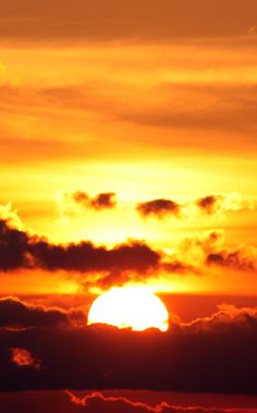 the sun is setting behind some clouds in the sky with an airplane flying above it