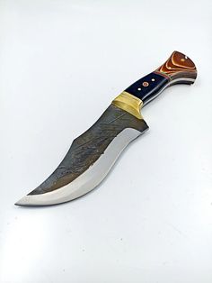a knife that is sitting on top of a white surface with gold trimmings