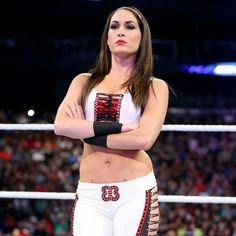 a female wrestler standing in the middle of a wrestling ring, with her arms crossed