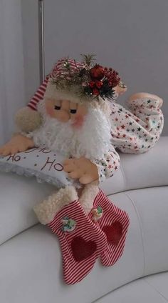 a stuffed santa clause sitting on top of a white couch