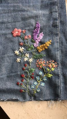 a pair of jeans with embroidered flowers on them