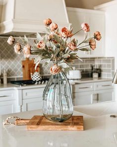 a vase filled with flowers sitting on top of a kitchen counter next to a cutting board