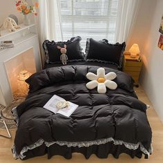 a bed with black comforter and white flower on it