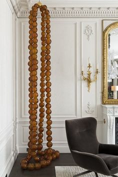 a room with a chair, mirror and wooden beads on the floor in front of it