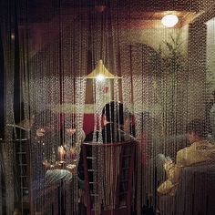 several people sitting at a table in a room with beads on the walls and floor