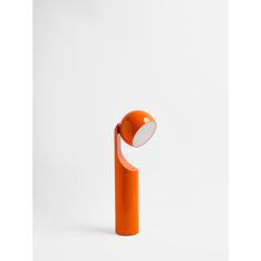 an orange table lamp with a white light in the middle on a white background,