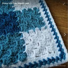 a blue and white crocheted blanket sitting on top of a wooden table