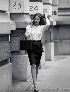 a woman is walking down the street with her hand on her head and holding a purse