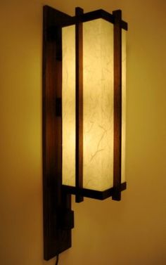 a wall mounted light with a white glass shade on it's back panel and wooden frame