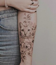 a woman's arm with a cat and flowers tattoo on the left side of her arm