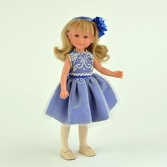 a doll with blonde hair wearing a blue dress and white shoes, standing in front of a white background