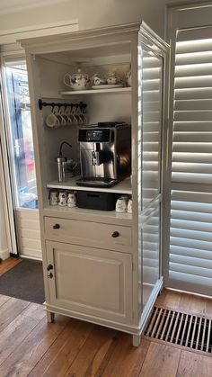 a coffee maker is built into the side of a cabinet in a kitchen with wooden floors