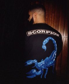 a man wearing a scorpion t - shirt in the dark