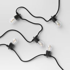 three light bulbs connected to each other on a white surface with black cords and plugs