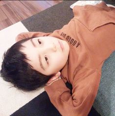 a young boy laying on the floor with his hands under his chin and eyes closed
