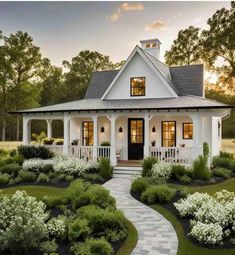 a white house with lots of windows and bushes around the front yard, surrounded by greenery