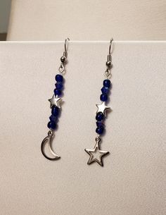 pair of earrings with blue beads and silver stars hanging from the earwires on a white surface