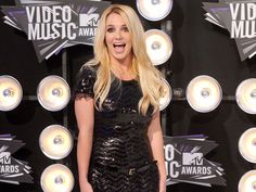 a blonde woman in a black dress on the red carpet at an awards event with her hands in her pockets