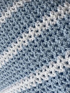 a close up view of a blue and white crocheted blanket