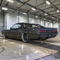 a black car parked in a garage next to a wall with lights hanging from it's ceiling