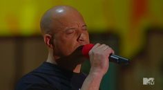 a bald man holding a microphone up to his face